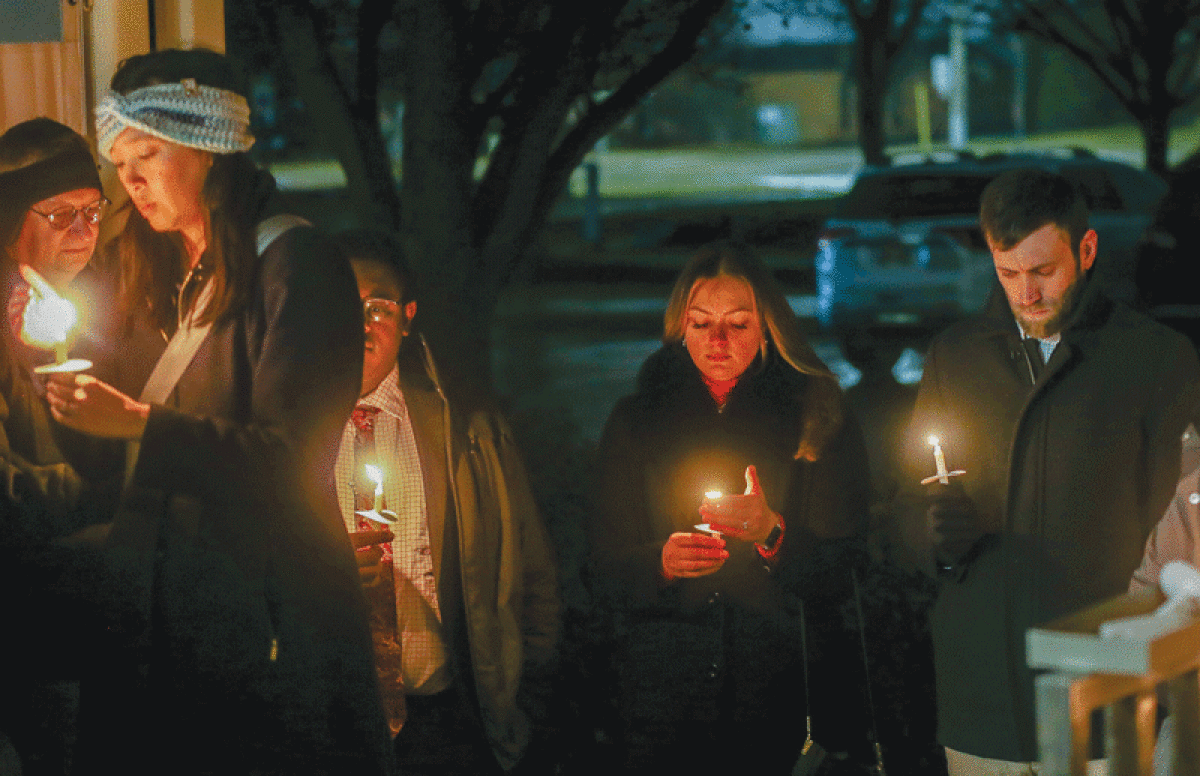   At a peace vigil on MLK Day Jan. 16, attendees lit candles in front of Madison Heights City Hall and shared a moment of silence and prayer. Rain caused the  vigil to be moved from the front of the gazebo to under the awning of City Hall.  