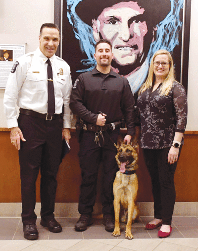  From the left, Sterling Heights Police Chief Dale Dwojakowski, police Officer James Sribniak and Kaylee Marcum  stand around the Police Department’s new K-9 dog, Dusty. 