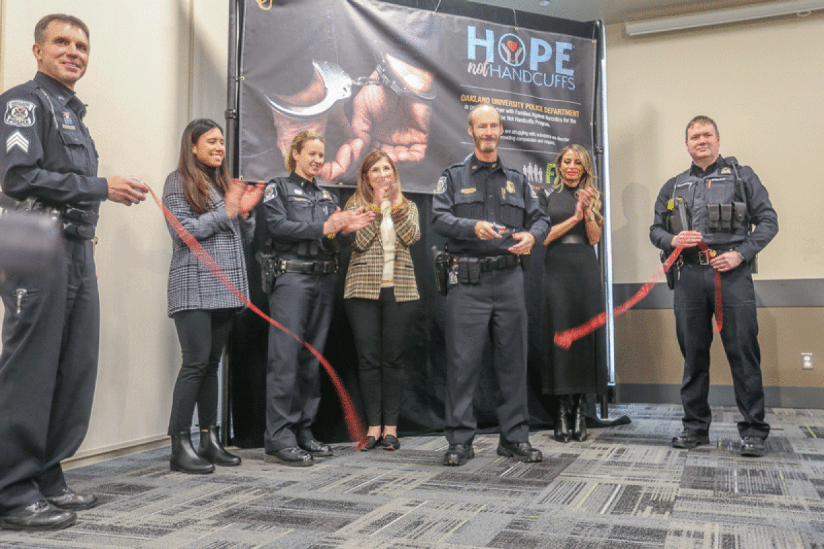   Oakland University Police Chief Mark Gordon cuts the ribbon to signal the start of the Hope  Not Handcuffs program at the university. 