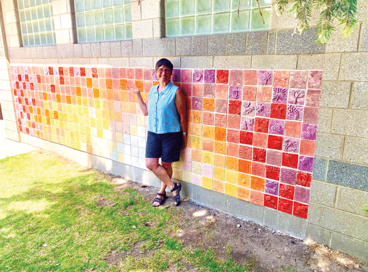  Huntington Woods-based mixed media artist Michelle Sider stands alongside the tile mosaic she designed and assembled at  Spencer Park in Rochester Hills. 
