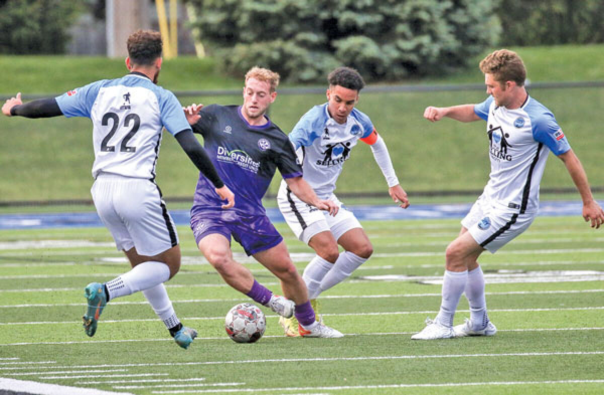 Oakland County Football Club midfielder Jack Streberger, a Grosse Pointe Woods native and returning veteran for the Purple Gang, fights to keep control of the ball from a swarm of Lansing City players during OCFC’s home opener in 2023. 