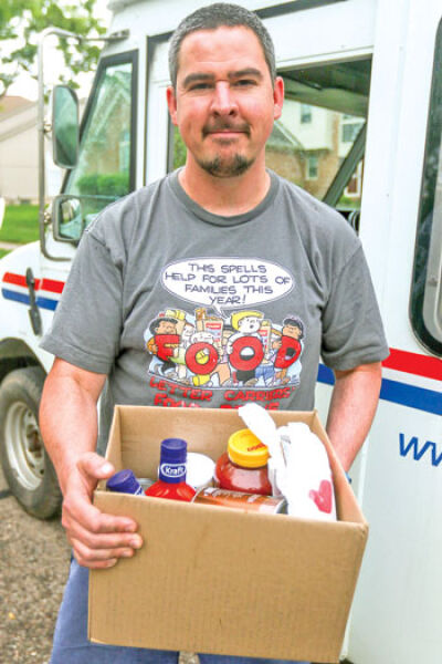  Letter carrier David Fabiszewski holds food collected in a Novi subdivision during last year’s Stamp Out Hunger Food Drive. 