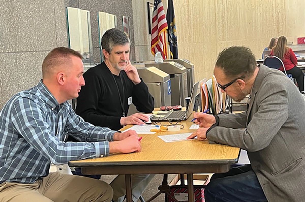  In this photo provided by attorney Jack Dolan, Fouts looks over the document in front of Michigan Department of State Bureau of Elections employee and notary David Foster, in the blue shirt. 