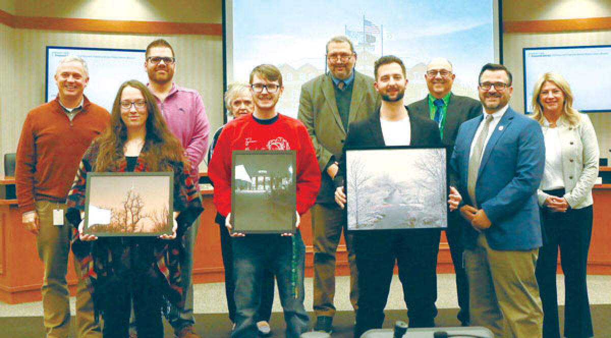  Brittney Reno, foreground left, Tyler Bucholtz and Justin Vollbach pose with the Macomb Township Board of Trustees and their winning photos from the township’s winter 2024 photo contest on May 8.  