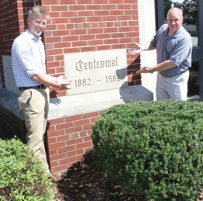  Senior Pastor Justin Krupsky, left, and Principal Bruce Volkert, right, stand near a cornerstone on the Trinity Lutheran Church & School building in Utica. 