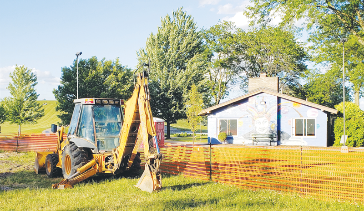  An excavator idles at the end of the day June 6 amid torn-up turf where a bandshell is being constructed at Civic Center Park. In the background is the Jaycee shelter building featuring “The Power of Imagination” mural by Jennifer Ramirez. The mural was the first initiative by the Madison Heights Arts Board, and the bandshell is its latest.  