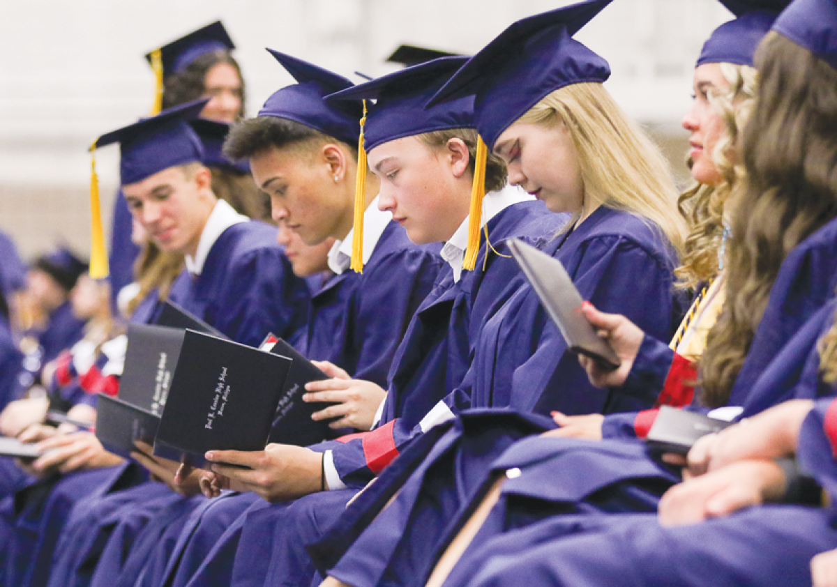  After walking the stage, a group of Cousino High School graduates look at their diplomas. 