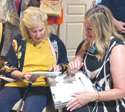  Longtime Helm supporter Marlene Boll, of Grosse Pointe Shores, receives a special photo album from Helm Executive Director Krista Siddall during a June 5 portrait unveiling at The Helm in Grosse Pointe Farms.  