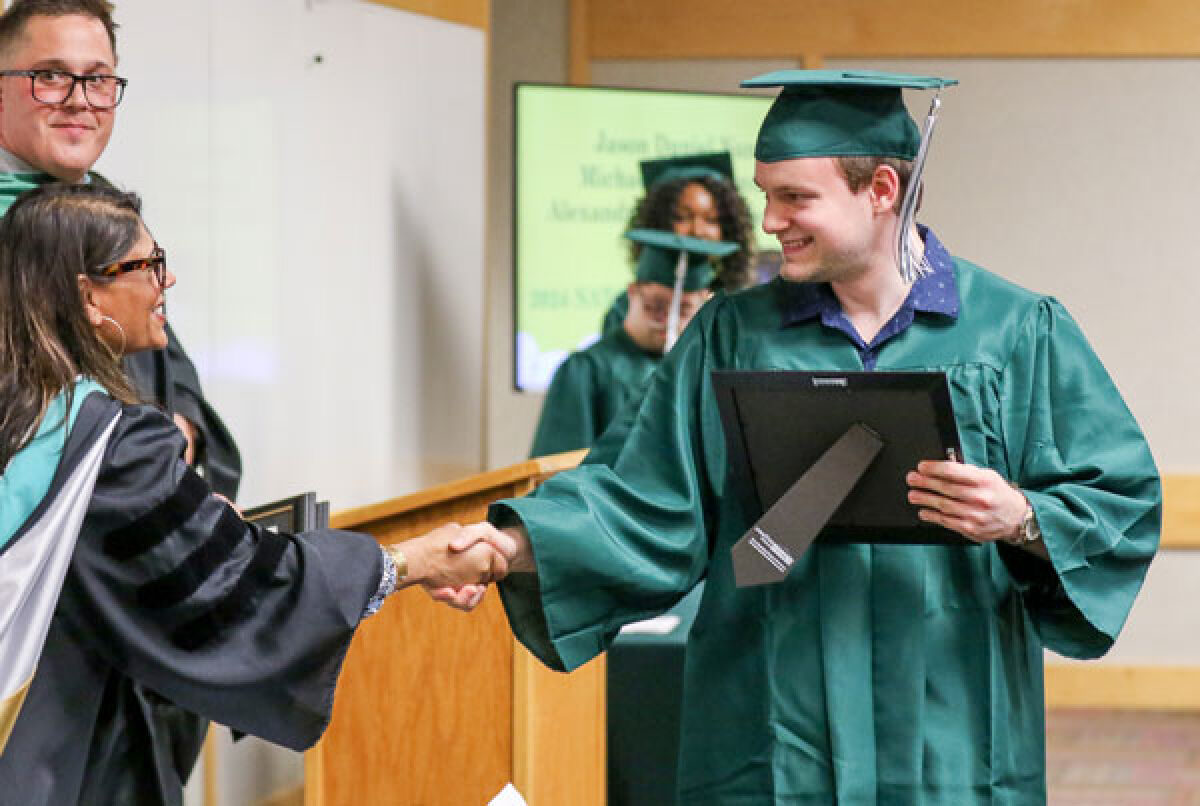  Jason Nunez receives his certificate and shakes hands with Shailee Patel, the Novi Community School District’s director of special education programs and services., during the Novi Adult Transition Center 2024 Graduation ceremony June 4 