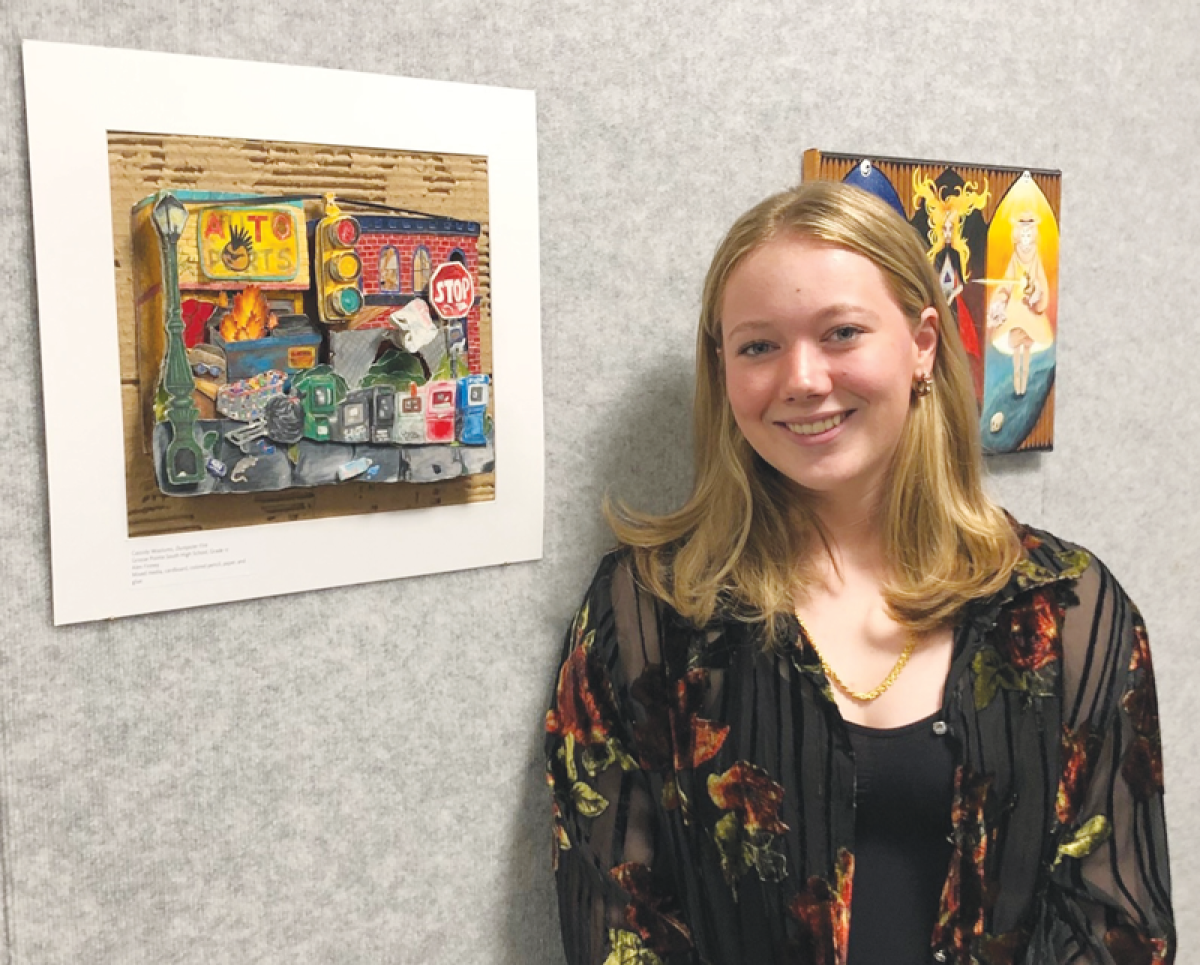  Recent Grosse Pointe South graduate Cassidy Woolums stands next to her mixed media piece, “Dumpster Fire,” which is now on view at the Detroit Institute of Arts. 
