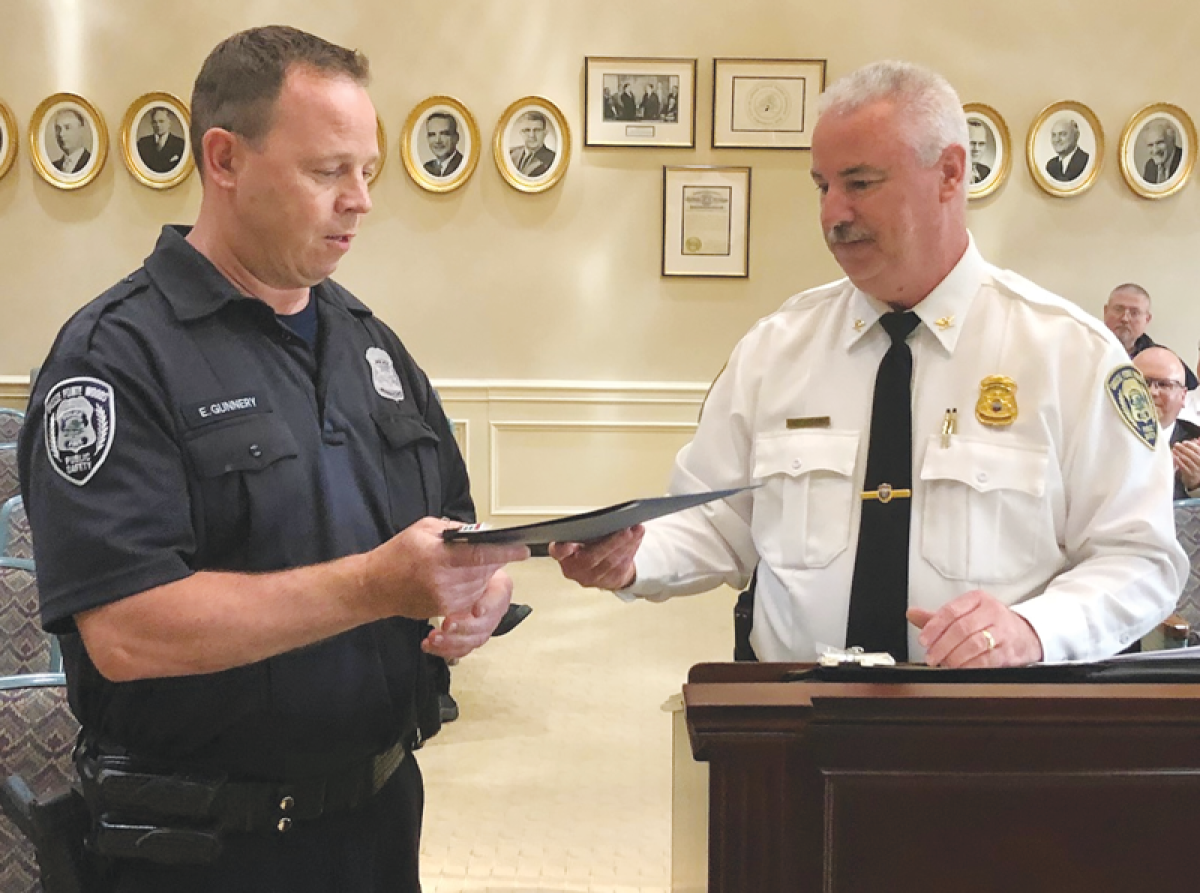  At right, Grosse Pointe Woods Public Safety Director John Kosanke presents officer Eugene Gunnery, left, with an award for saving a newborn’s life.  