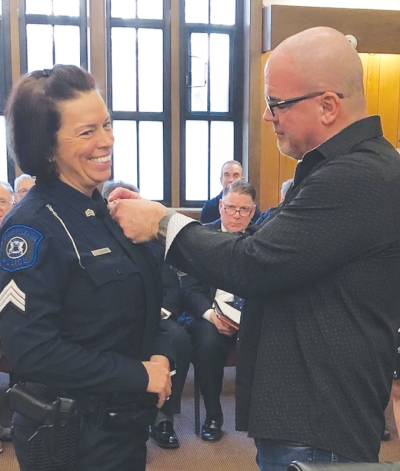  Grosse Pointe Farms Public Safety officer Veronica Cashion’s new sergeant badge is pinned on her uniform by her husband, Jim, a lieutenant in the Detroit  Police Department.  
