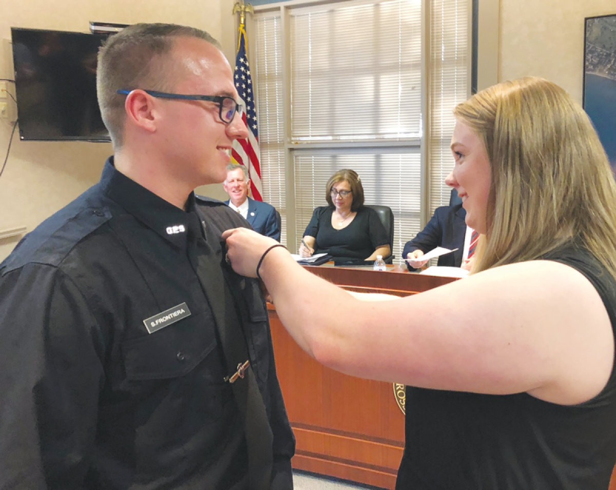  After being sworn in, new Grosse Pointe Shores Public Safety officer Sean Frontiera’s badge is pinned to his uniform by his  wife, Katy. 