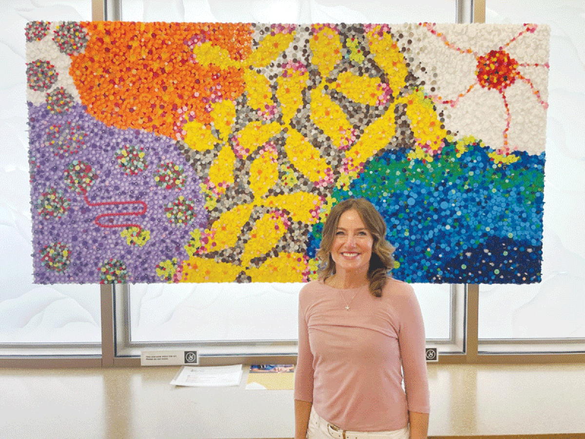  Donna Dzialo, of Rochester, a nurse anesthetist at Ascension Providence Rochester Hospital, created the “COVID Time CAPSule” from discarded drug vial caps. The artwork includes the SarsCov2 virus, the four balls in the upper left corner; a purple cell infected with the virus and featuring an mRNA chain; white blood cells; an orange antibody-producing cell; yellow antibodies; a natural killer cell, at the top right of the piece with the long skinny arms; and healthy cells, at the bottom right. 