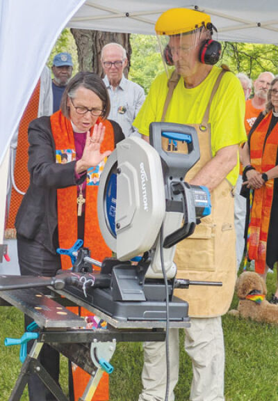  Episcopal Bishop Bonnie A. Perry blesses one of the six chop saws at the June 18 demonstration. 