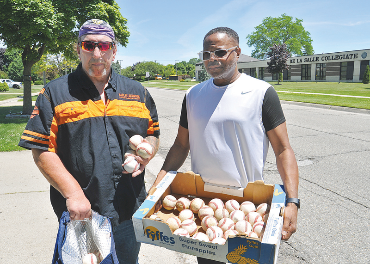   Neighbors George Johnson and Nathaniel King show the balls they have collected. “This is just what was left after they retrieved the others,” Johnson said.   