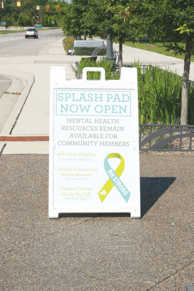  A sign announcing that the Brooklands splash pad is open also includes information for mental health resources for community members. 