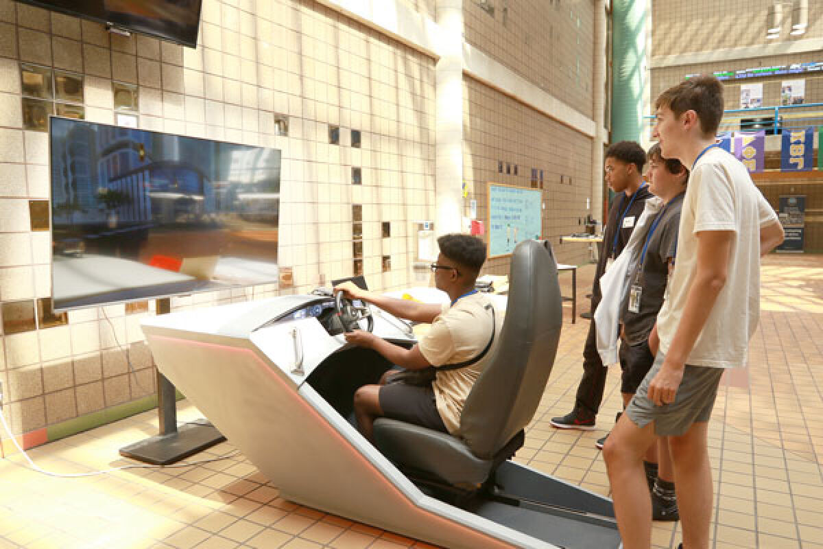  Attendees of the open house try out a demonstration of the new road technology simulator at Lawrence Technological University. 