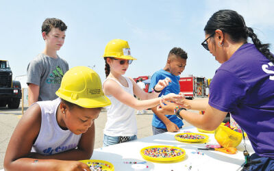  From left, Adryanna Faith Brown, 8, of Clinton Township; Nellie Blehm, 11, of Fraser; and Isaac Brown, 10, of Chesterfield Township, work on making bracelets with the help of Caila Domingo, 19. The event offered a “Family Fun Zone” in addition to the car show. 