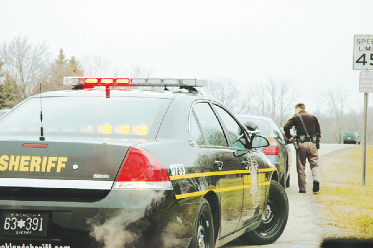  A deputy from the Oakland County Sheriff’s Office approaches a vehicle during a traffic stop. 