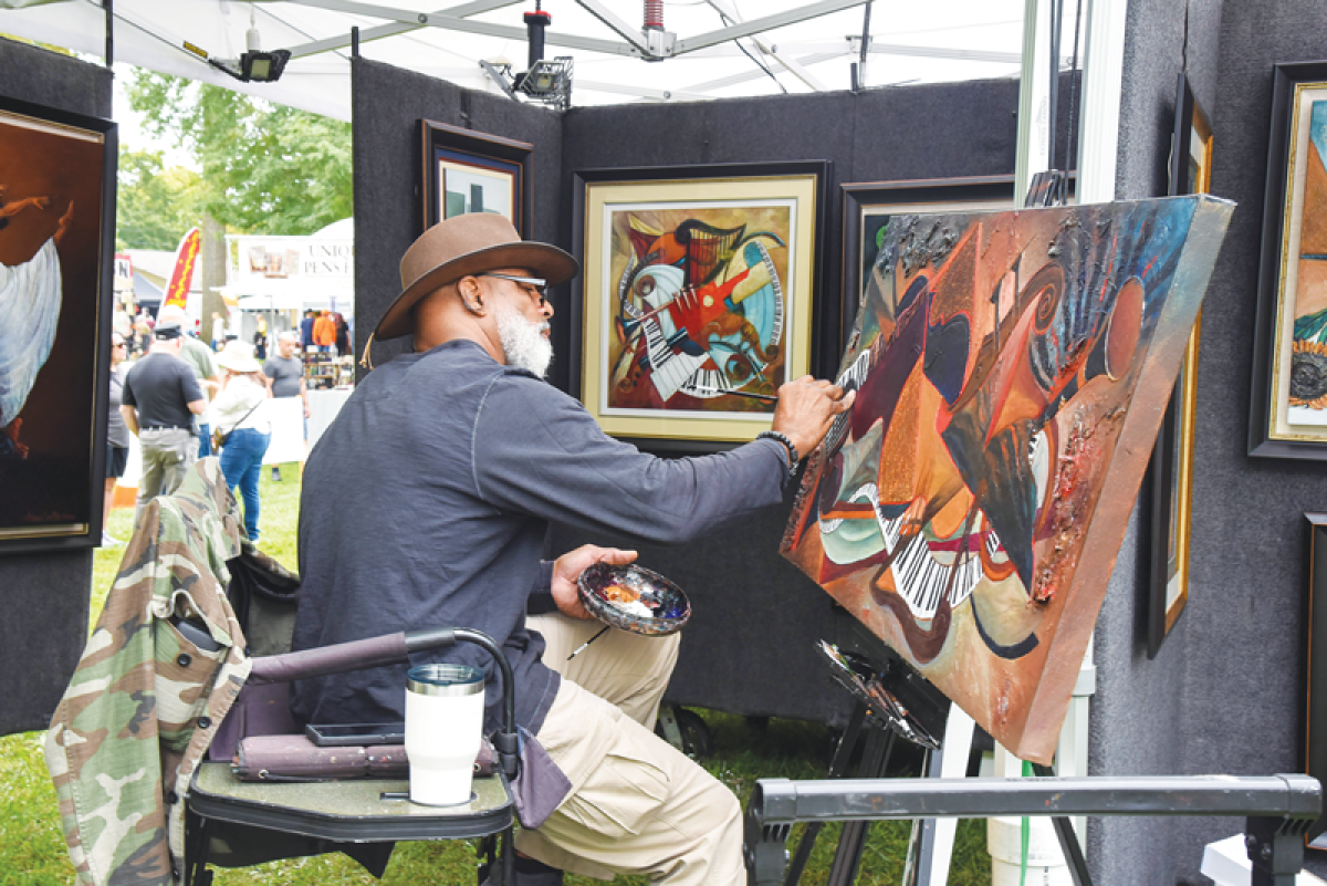   An artist works on a painting in his booth during  a past Art and Apples Festival.  