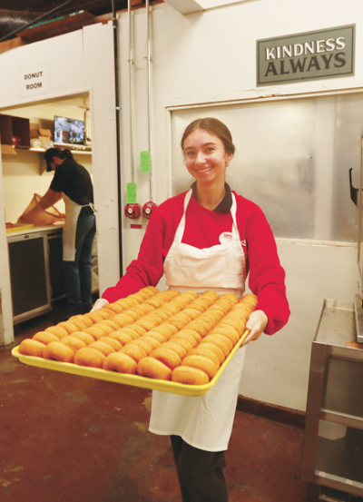  Yates Cider Mills staff member Ava Ramales, 17, of Shelby Township, takes out dozens of freshly baked doughnuts. 