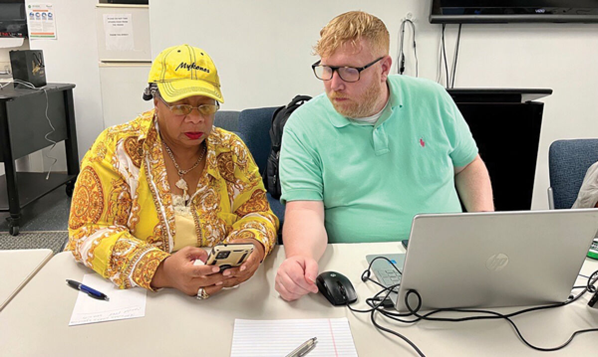  Regina Cobb, left, of Lathrup Village, learns technology skills on her device with New Horizons Computer Trainer Ryan Randall, right. 