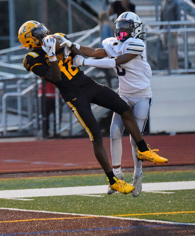  North Farmington senior wideout Lorence Woodley makes a leaping grab over a Farmington defender as North Farmington defeated Farmington 20-7 Sept. 13 at North Farmington High School. 