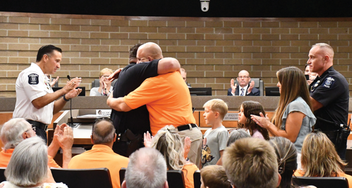  Scott VanLuven, wearing an orange shirt, gets a hug while being honored for his role in the rescue of a young girl who police say was in the process of being abducted at Clinton River North Park Aug. 13. VanLuven is a member of the Sterling Heights Police Department’s Citizens on Patrol volunteer group.  