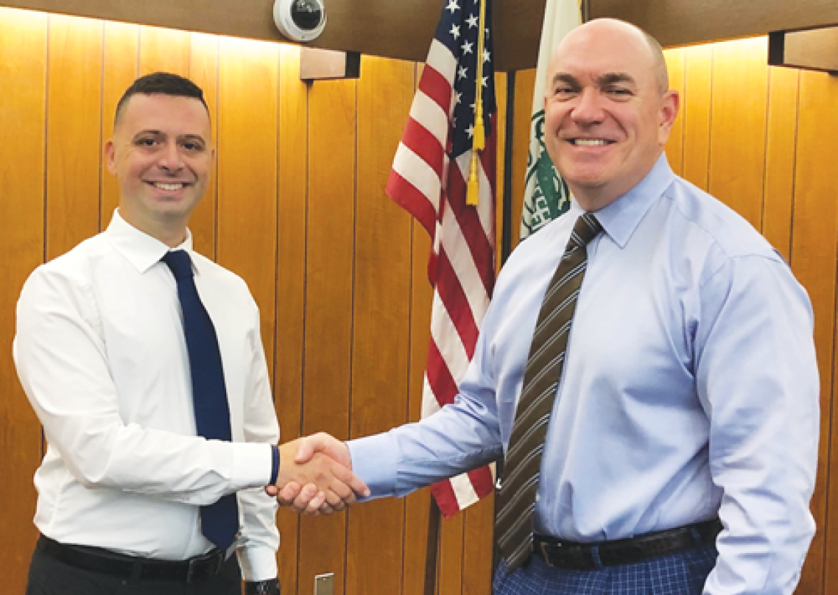  After being sworn in, new Farms officer Kevin Khoury is congratulated by Public Safety Director John Hutchins. 