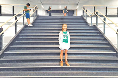  Nina Padilla, a sixth grader at Novi Meadows, encourages guests at the open house to come up to the second floor as her classmates wait to welcome them. 