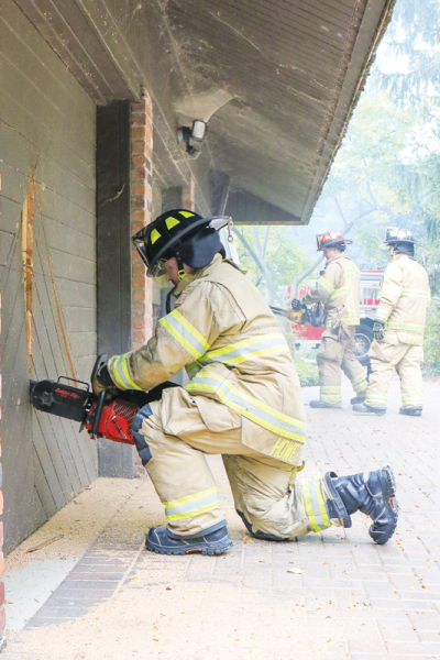   Grosse Pointe Shores public safety officer Billy Howe uses one of the department’s specialty tools as he tries to cut a hole in a garage door during a fire training exercise Sept. 26 at a home in the 800 block of Lake Shore Road slated for demolition.  