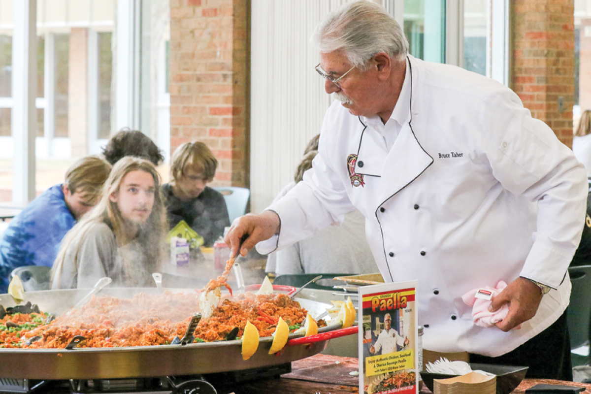  Taher Inc. CEO Bruce Taher — on a visit to North Sept. 25 — adds shrimp to the Spanish paella he made for students and staff.  