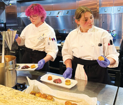  Schoolcraft College Culinary Arts students Barley Guadagnini, left, and Lainey Woodman plate the roasted venison loin with a potato cake, maple butternut squash and wild blueberry sauce. 