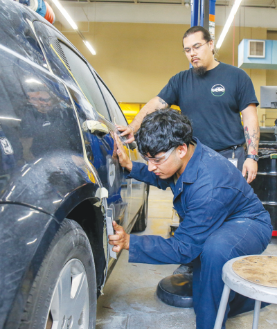  Antonio Acuna guides Avondale High School junior, Angel Mendoza through a dent repair in collision repair and refinishing course at Oakland Schools Technical Campuses-Northeast. 