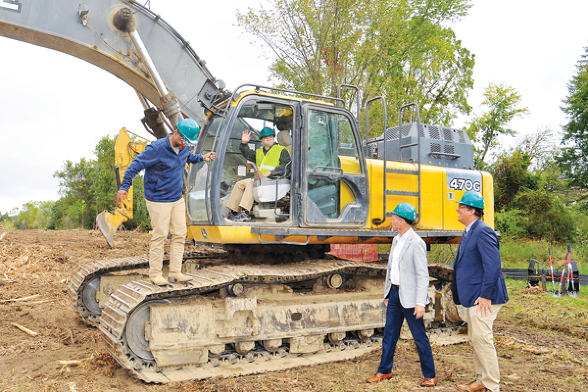  Matt Cooney sits inside an excavator to break ground on the site of Walton Oaks, a “neuro-inclusive” neighborhood Sept. 25. Once the homes are completed, Cooney is planning on moving into a home with four friends, including Carly Guy. Joining him on the ground are Oakland County Executive Dave Coulter, center, and David Woodward, chair of the Oakland County Board of Commissioners. 