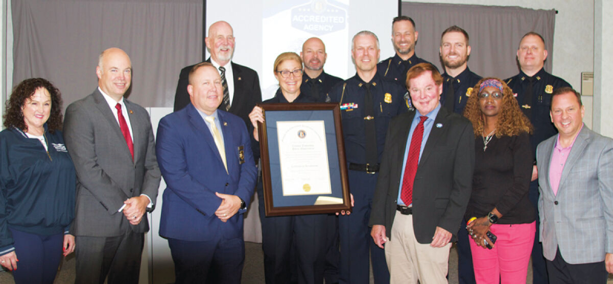  Clinton Township Police Chief Dina Caringi holds up a certificate of accreditation at the Clinton Township Police Department’s ceremony on Oct. 9. Caringi is flanked by members of the police department and the township’s Board of Trustees. 