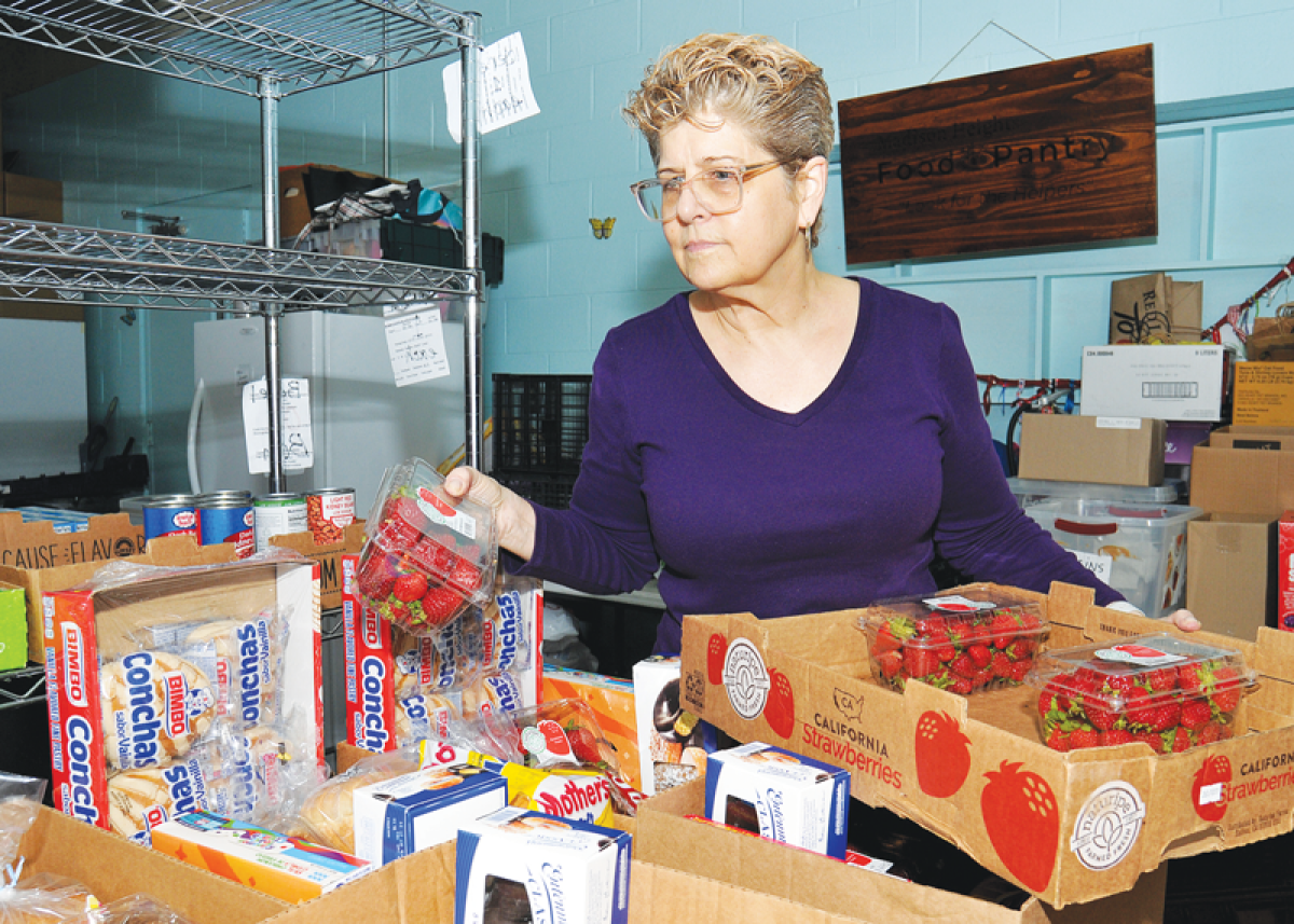  During a distribution Oct. 19 at the Madison Heights Food Pantry, located inside borrowed space at Central Church, volunteer Kathy Trastevere places fresh strawberries into boxes.  