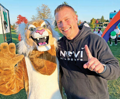  Ben Mainka, superintendent of the Novi Community School District, poses with Willy the Novi Wildcat during the tailgate party put on by the Novi and Northville educational foundations. 