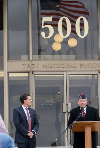  Mayor Ethan Baker and the audience at the Veterans Day Ceremony observe U.S. Retired Navy Lt. Todd R. Wodzinski reading “I Am The Flag,” by Howard Schnauber. 