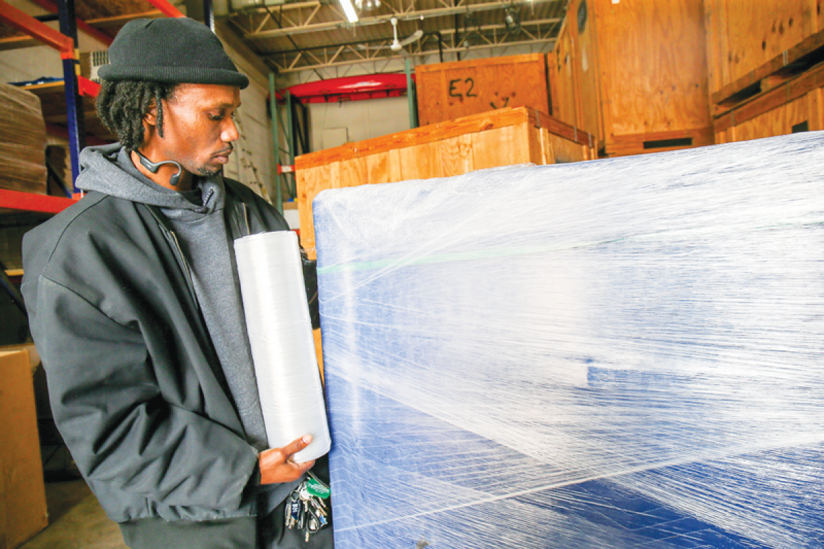  Marcus Jennison, operations manager of Two Men and a Truck in Fraser, demonstrates the padded wrapping that movers will use to protect furniture during a move. A blanket is used to wrap the furniture and then secured with shrink wrap.  