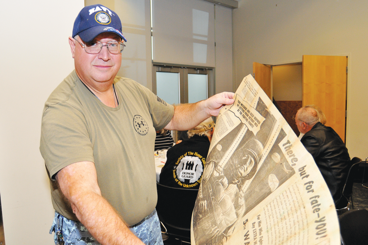  U.S. Navy veteran Guy Kaercher, of Warren, holds up a June 28, 1944, Detroit Times newspaper encouraging people to buy war bonds 22 days after the Allied invasion of Normandy during World War II.  