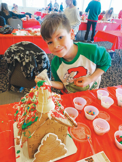  A child shows off a gingerbread creation during Twin Lakes Golf Club’s first Gingerbread House Challenge last year. 