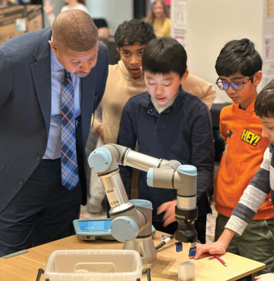  David Lewis, president of AT&T Michigan, watches as sixth grade students from Novi Meadows Elementary School show him how to work an industrial robot arm during the Student Technology Showcase at the Michigan State Capitol Dec. 4. 