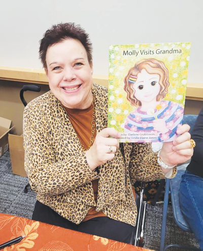  Darlene Grablowski, of Madison Heights, holds up a copy of her new book “Molly Visits Grandma” during the Authors Fair at the Troy Community Center Nov. 16. The book is inspired both by her own experiences visiting family on a farm, as well as the life of her late niece. 