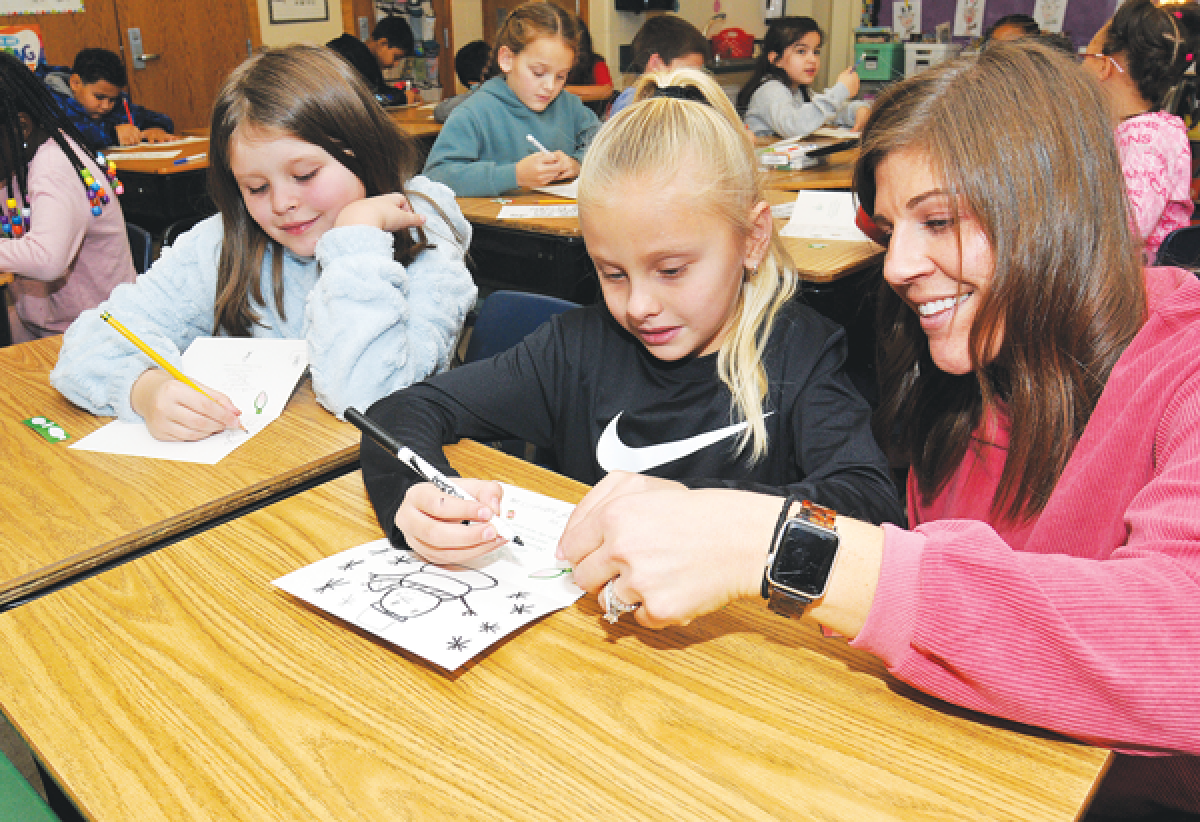  Green Acres Elementary School second-grade teacher Emily Houghton, right, assists Tanna Gordon and Nadia Kedzor with Christmas greeting cards for local senior citizens. 