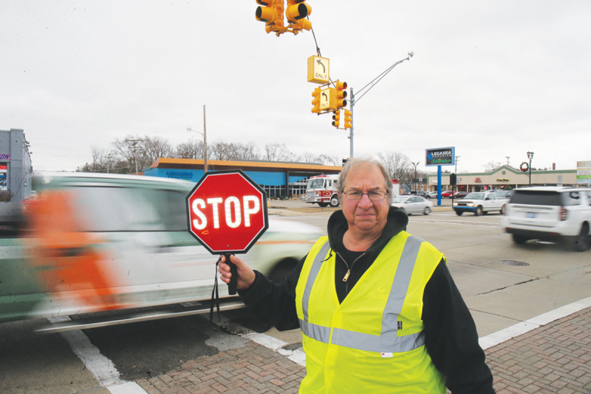  Utica Community Schools crossing guard Mike Delicata holds one of the two LED stop signs that the Utica Fire Department recently bought for crossing guards as traffic passes through the Van Dyke Avenue and Hahn Street intersection Dec. 11. 