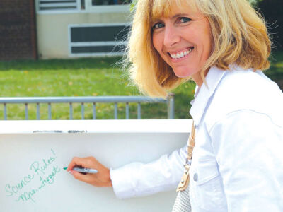  Kim Troost, a teacher at Novi Meadows Elementary School, autographs a beam to be used as part of the construction above the office in the school’s new building, which is set to open next year. 