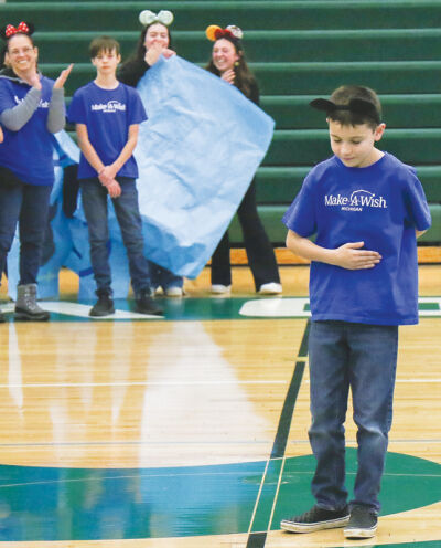  Henry Tudor, 8, of Farmington, bows to the crowd in the Novi High School gym Dec. 12 after learning that the students funded his wish to go to Walt Disney World through Make-A-Wish Michigan. 