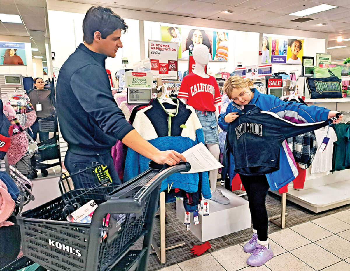  Novi firefighter Anthony Tocut helps a young girl shop for clothes during the annual Shop with a Hero event Dec. 14. The event helped underprivileged youth in the Novi Youth Assistance program pick out clothing and other necessities at Kohl’s in Novi. 